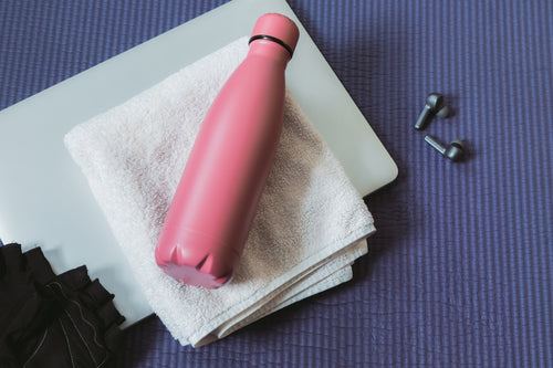 yoga mat flatlay with laptop and water bottle
