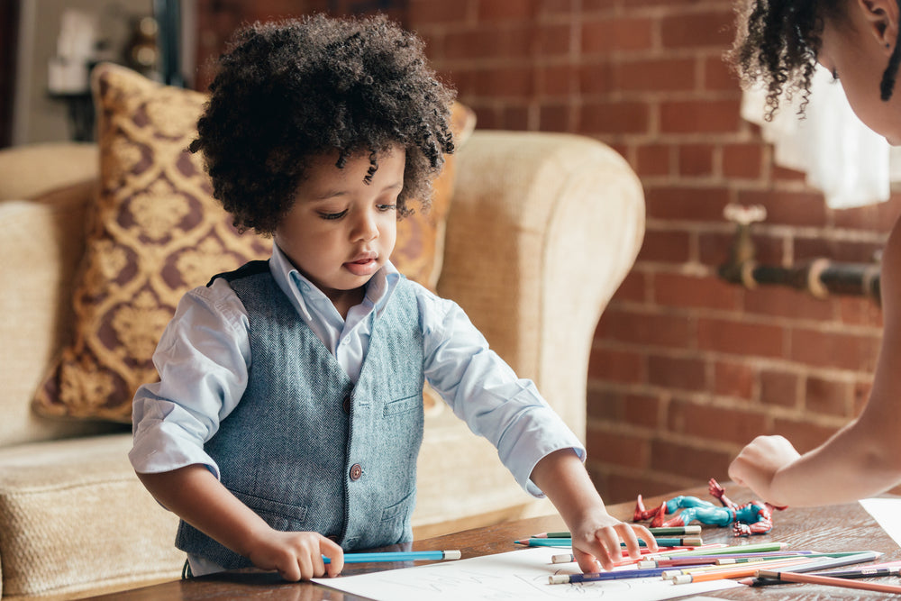 young boy drawing on coffee table