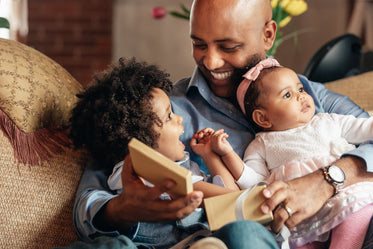 young boy smiles at father holding baby sister