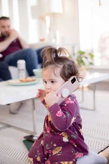 young child holding a conversation on a pink cell phone