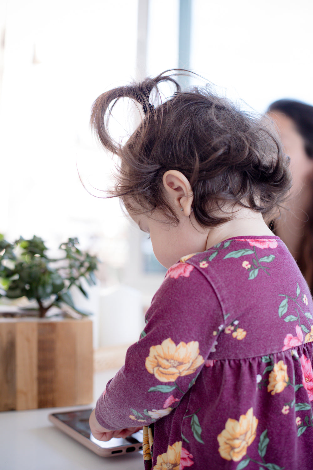 young child looks at a cell phone on a white table