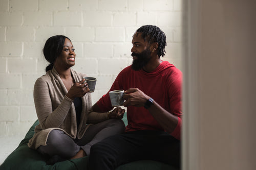 young couple laugh together with a coffee