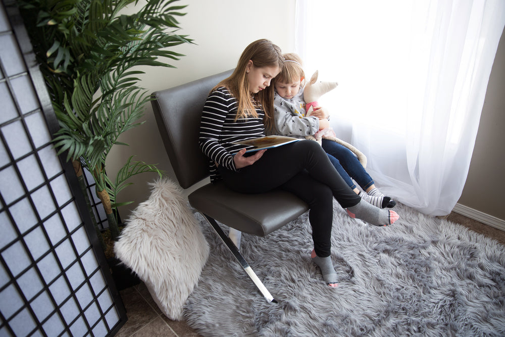 young girl reads to her little sister