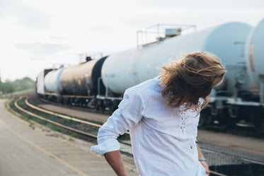 young man by trains at sunset