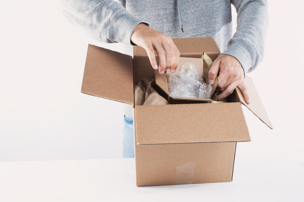 young man fills a box with packing