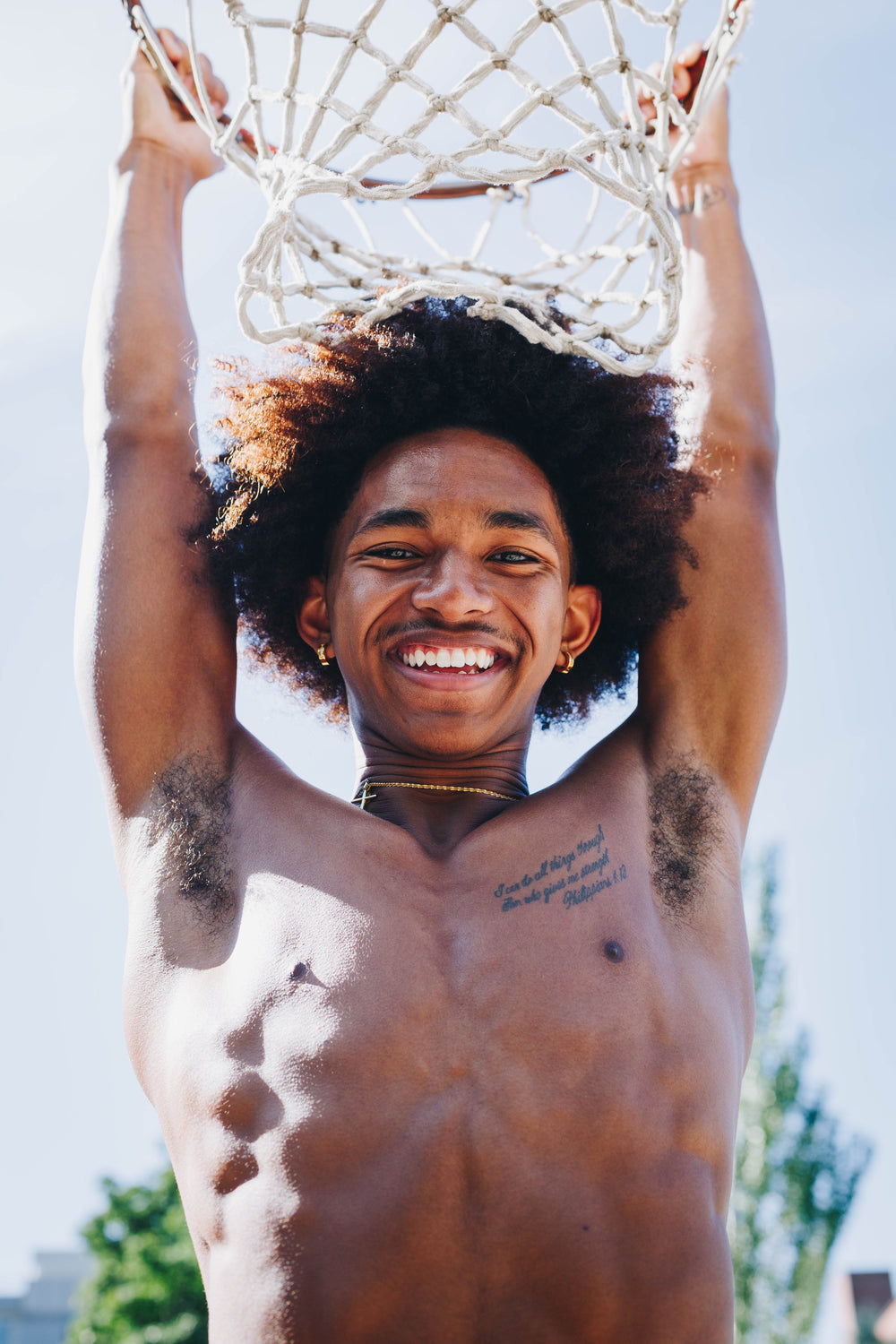 young man hangs from basketball net