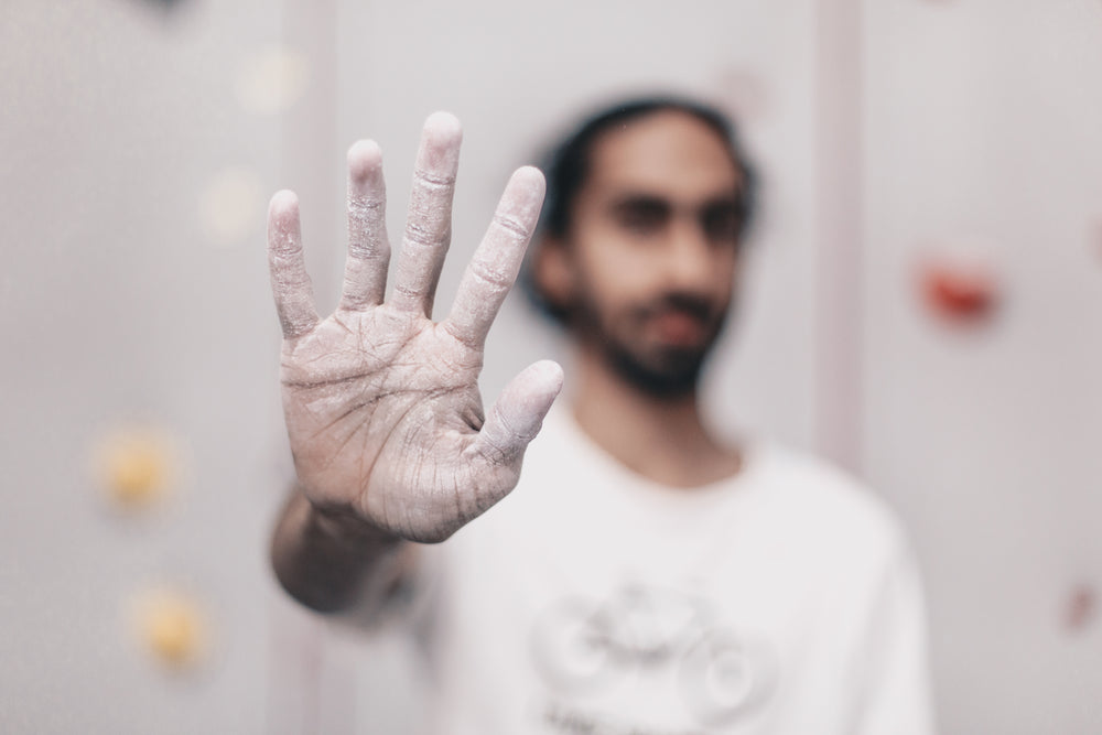 young man holding out chalk covered hand