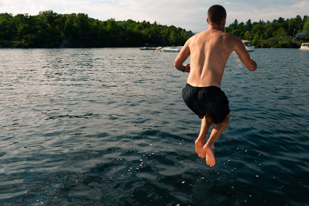 young man jumping into beautiful lake