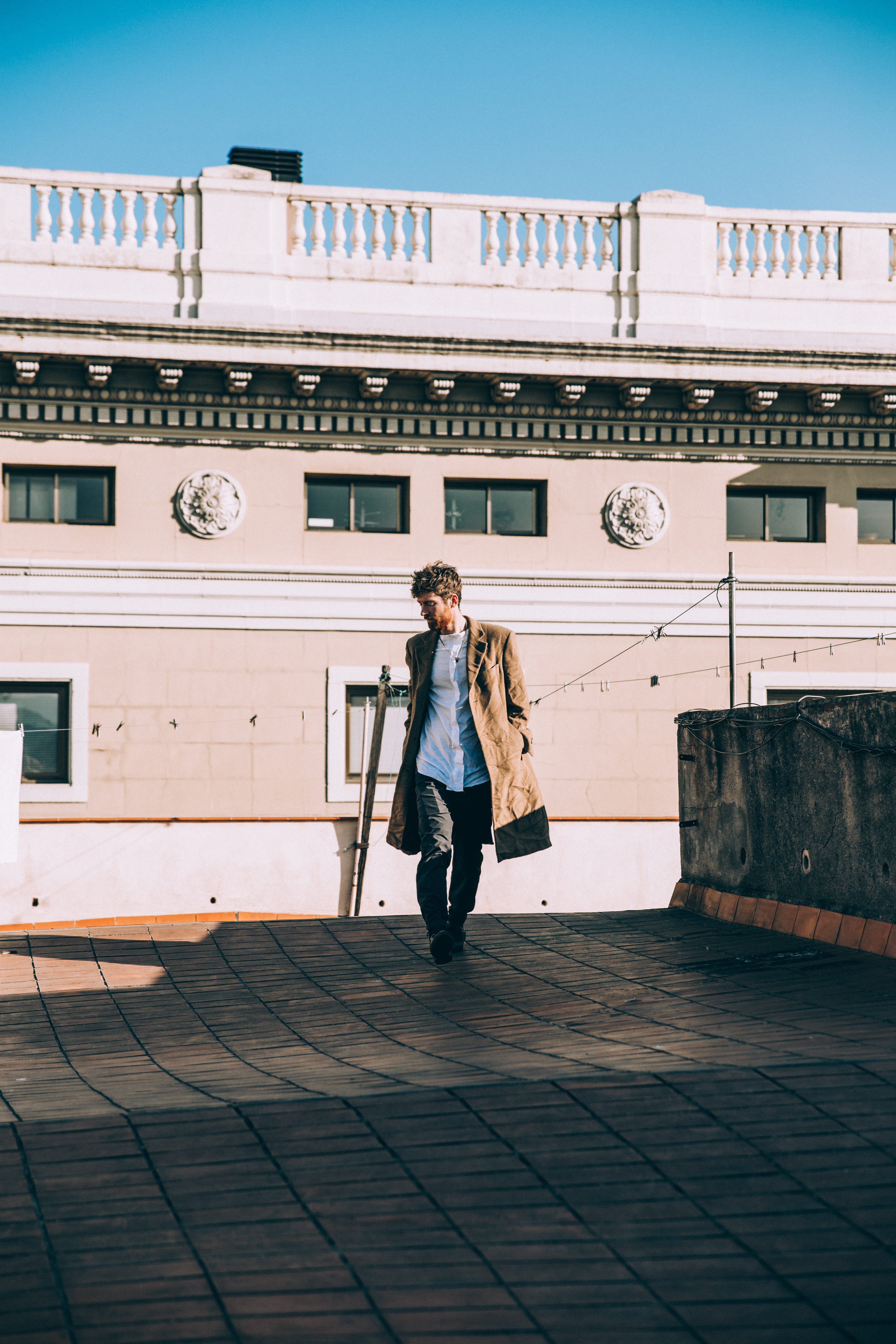 Young Man On Rooftop In Brown Coat