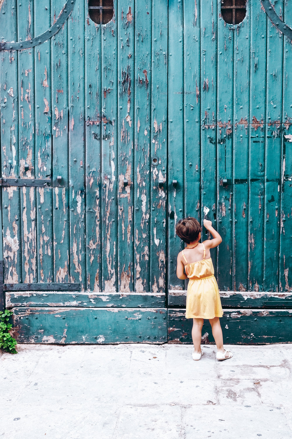 young person knocks on large blue doorway