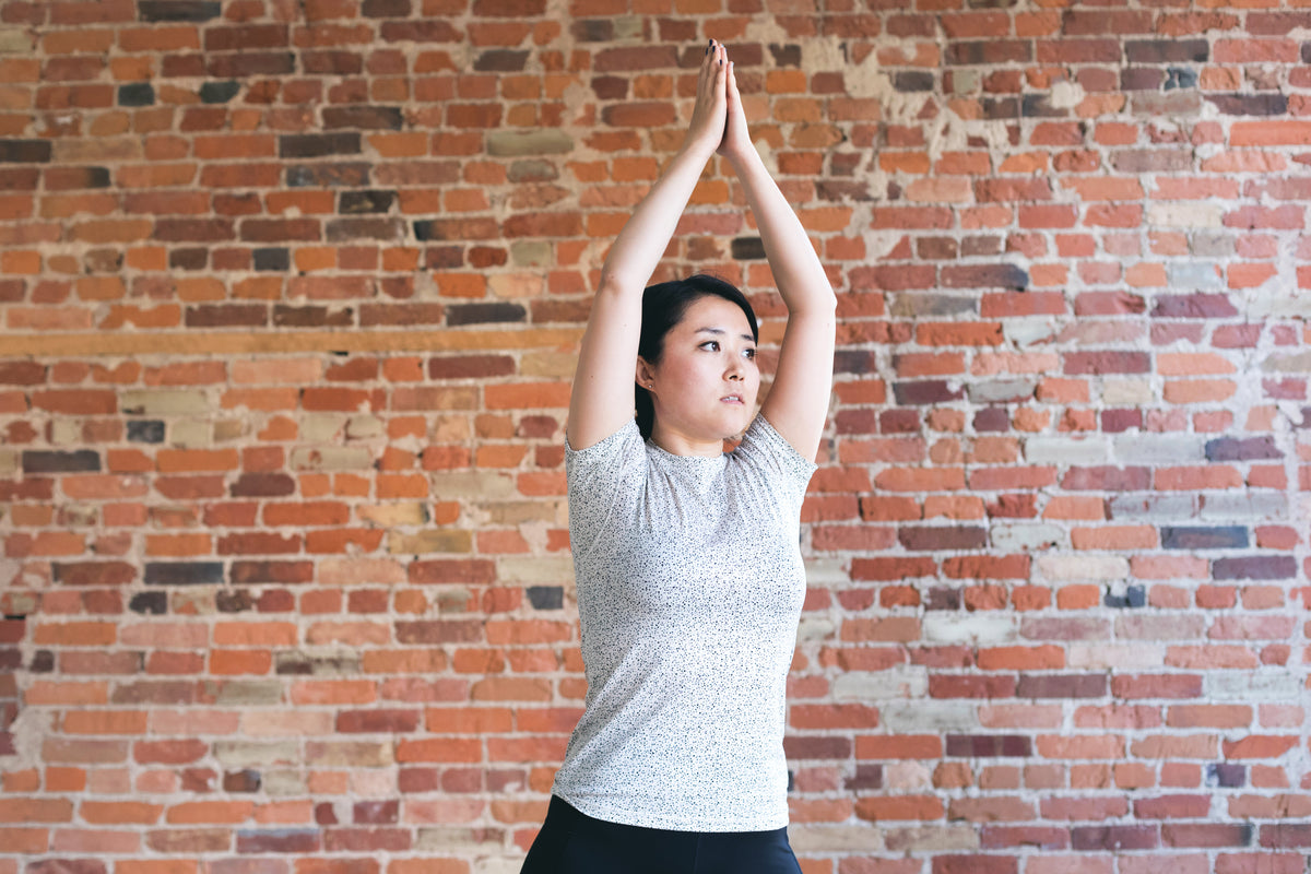 young woman against exposed brick doing yoga