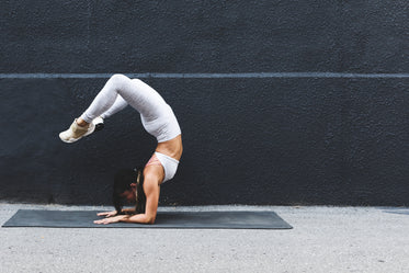 young woman doing yoga pose against black wall