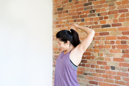 young woman exercising in workout clothes against brick wall