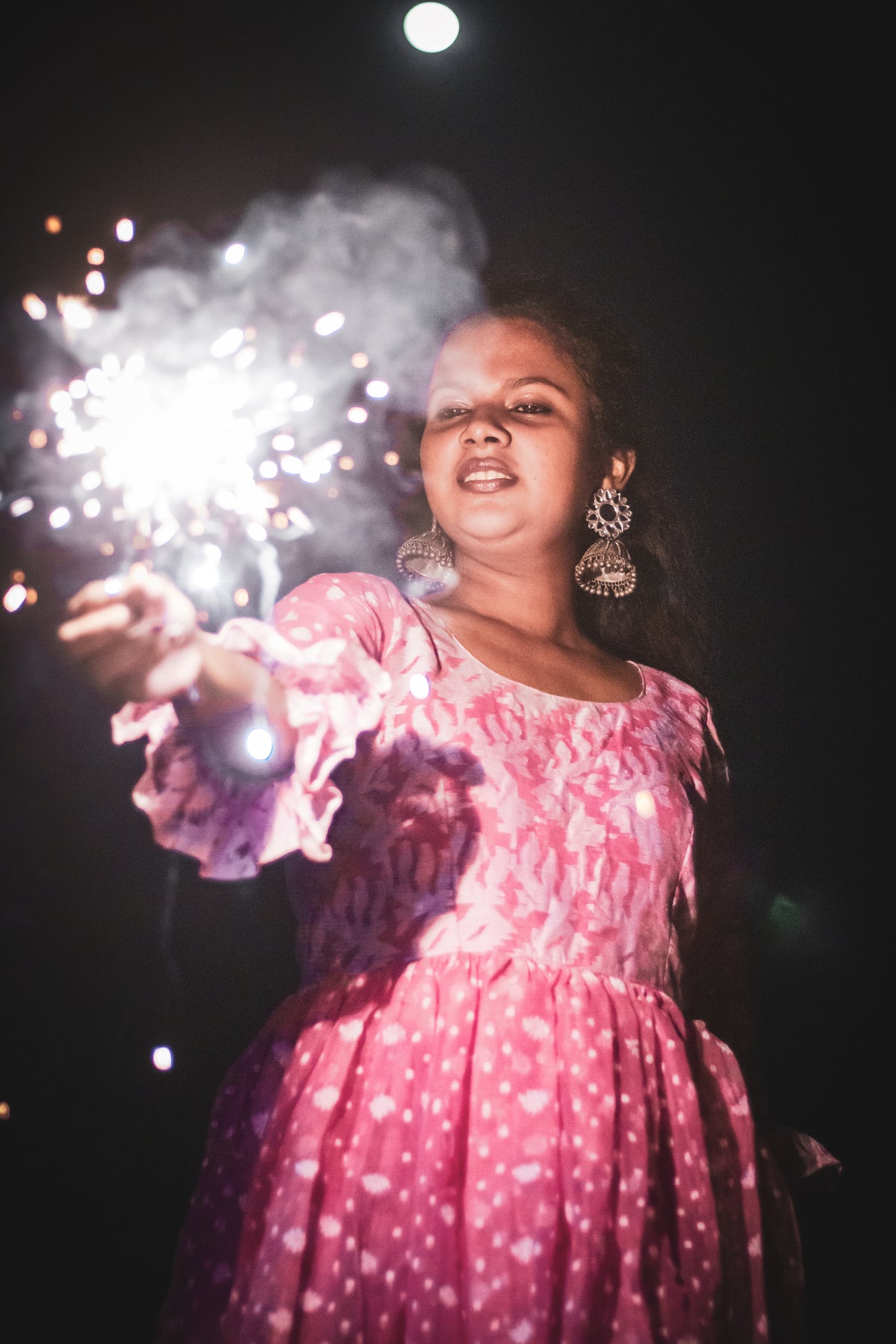 young woman holds out sparkler