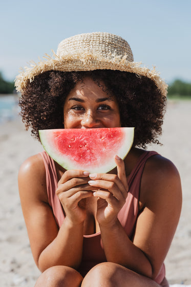 young woman holds watermelon slice on sunny beach