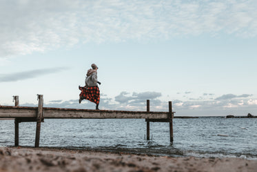 young woman in autumn clothing running across dock