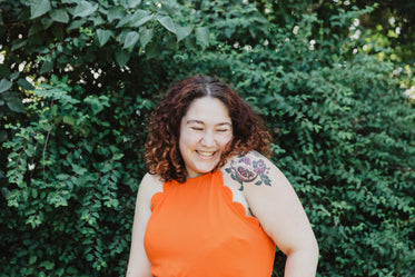 young woman in orange shirt with pomegranate tattoo