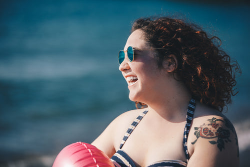 在阳光明媚的海滩上，年轻女子穿着泳衣，戴着太阳镜