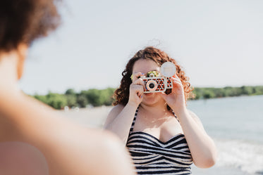 young woman in swimwear taking photo with colourful camera