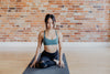 young woman in yoga pose against exposed brick
