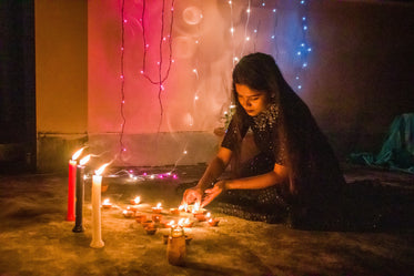 young woman lights candles for diwali
