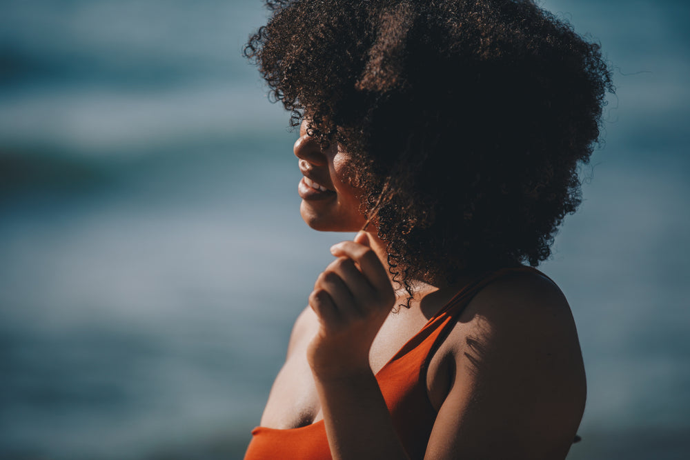 young woman on beach in swimwear teasing hair