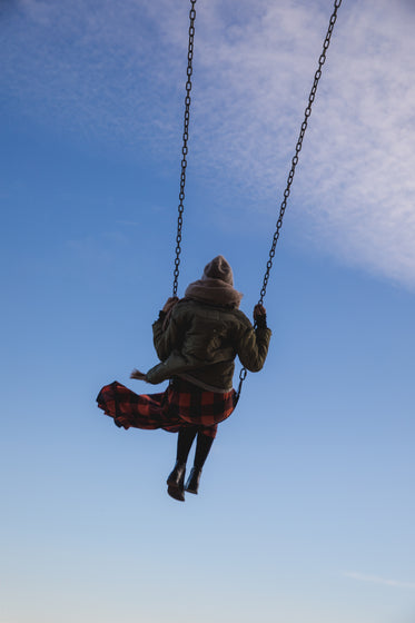 young woman on swing reaching to sky