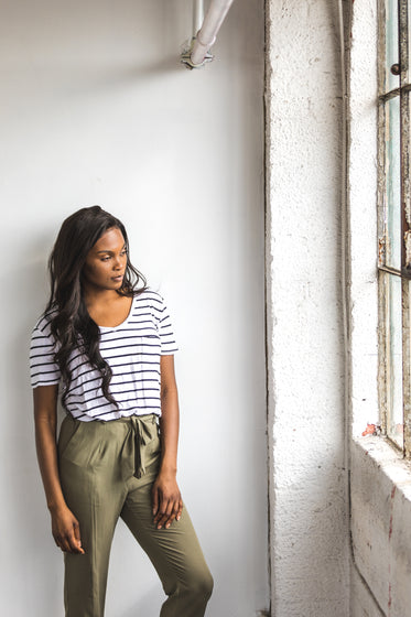 young woman poses in front of a large window