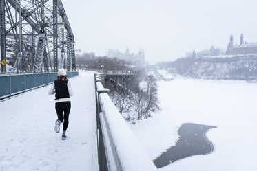 young woman running across a snowy bridge