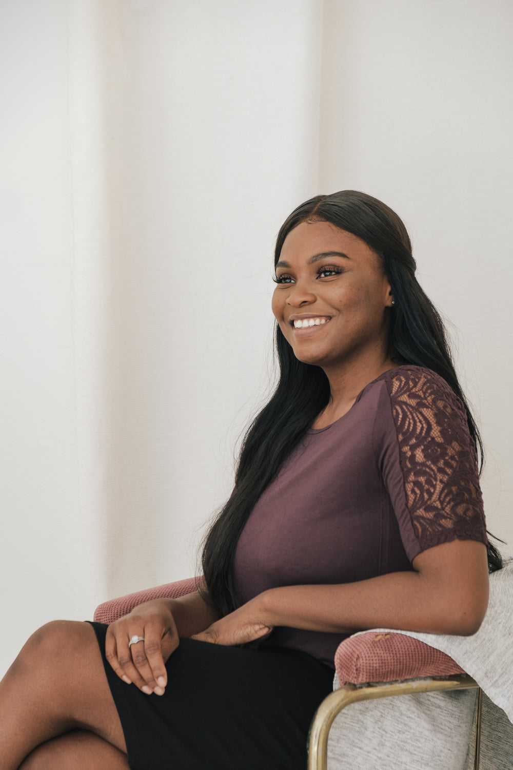 young woman sitting at an angle and smiling