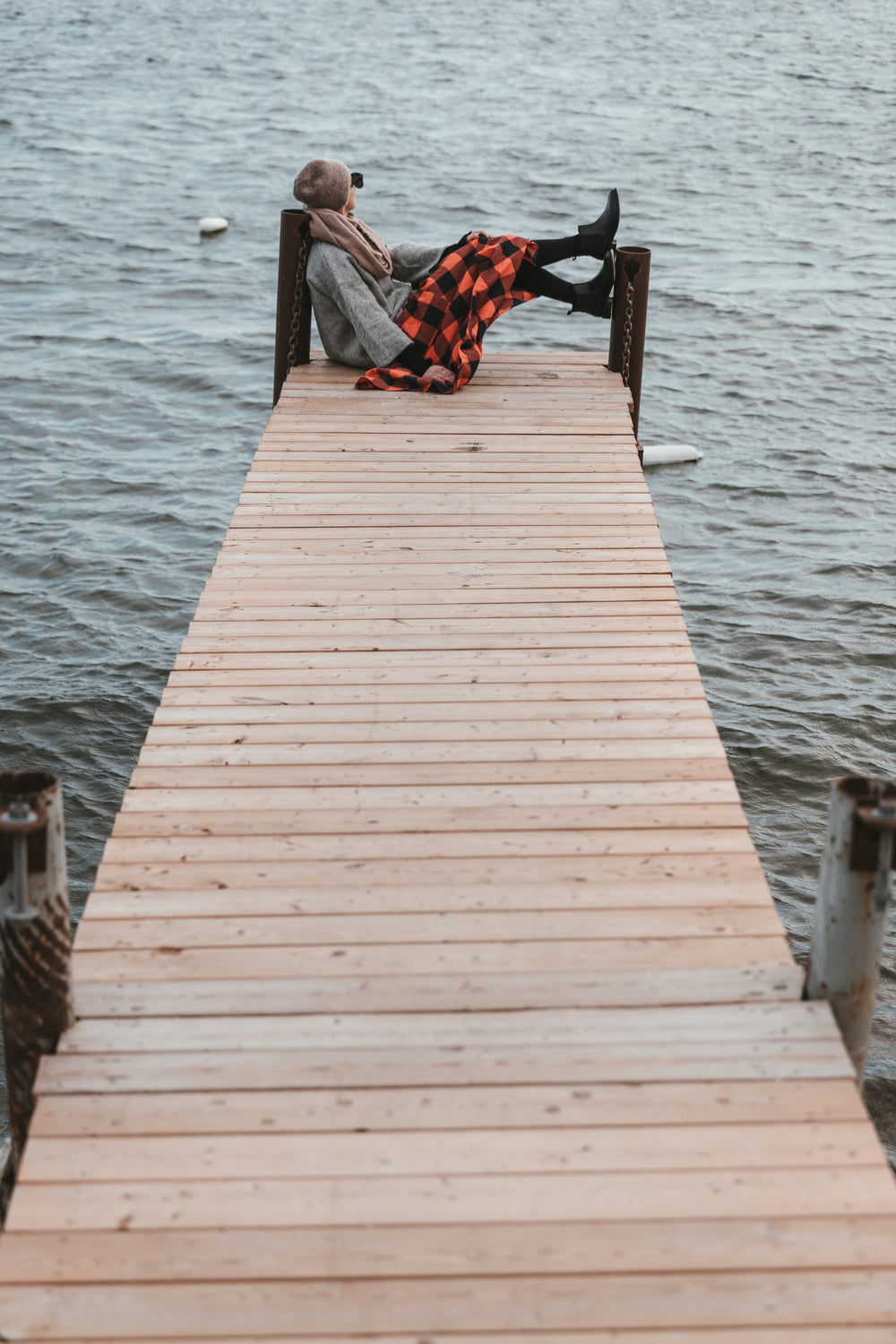 young woman sitting on a dock looking out to water