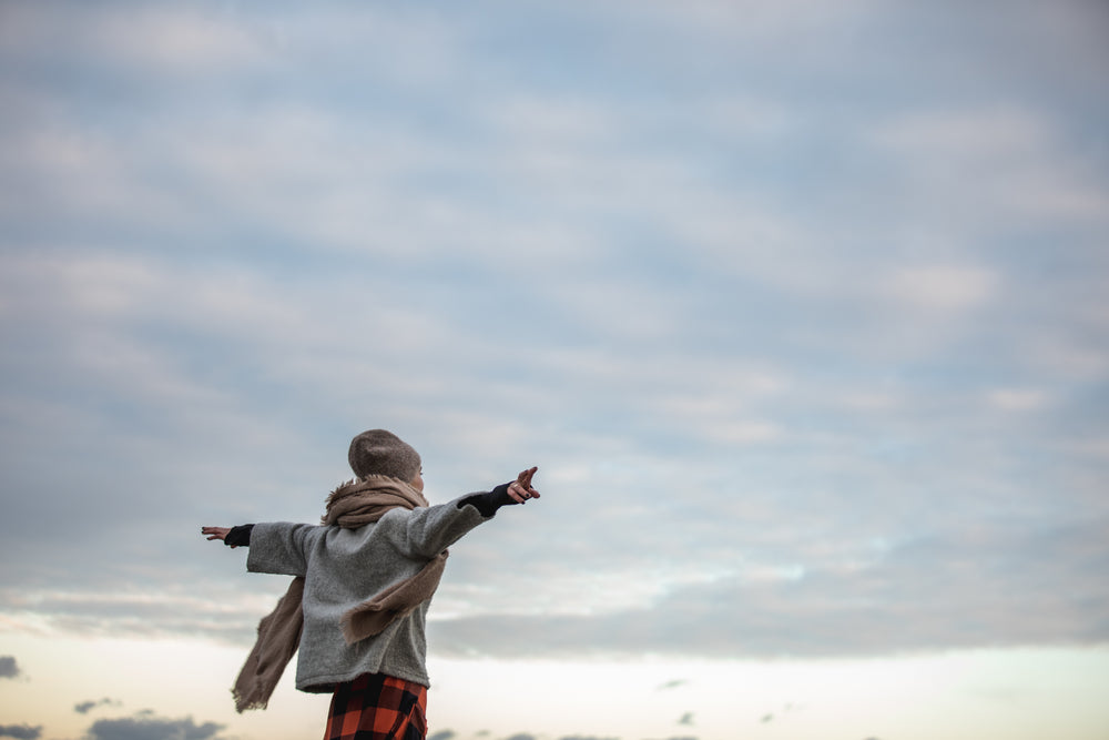 young woman spreading her arms in autumn breeze